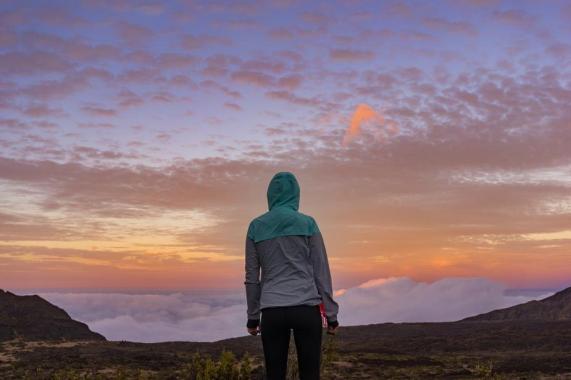 young-woman-standing-on-a-mountain-looking-over-the-clouds_925x